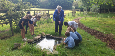 Eco Committee Team Members with Heather looking at the newly built pond. They are eagerly awaiting the arrival of frogs and newts!